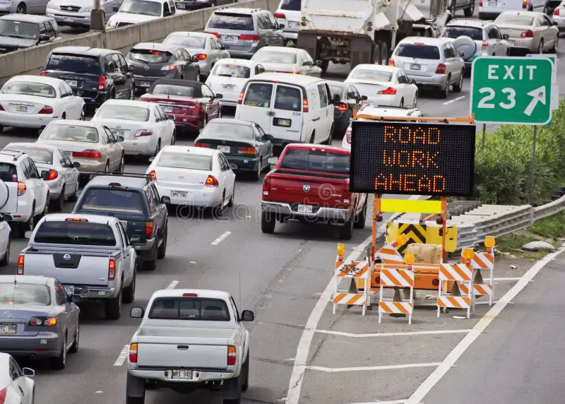 Highway traffic backup with Road Work Ahead electronic sign and construction barriers